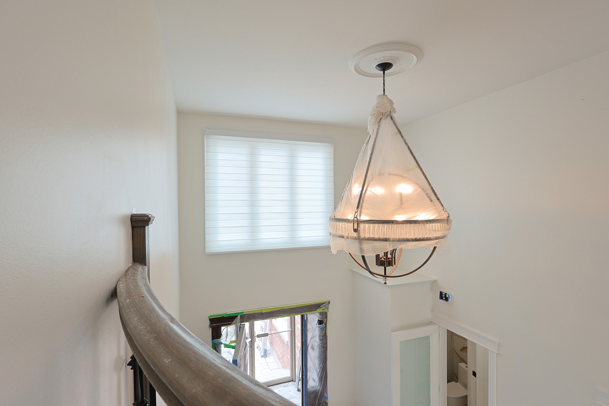 White custom blind installed beside an upstairs landing